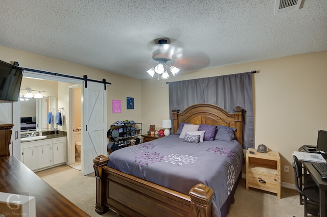 carpeted bedroom with connected bathroom, a barn door, a textured ceiling, sink, and ceiling fan