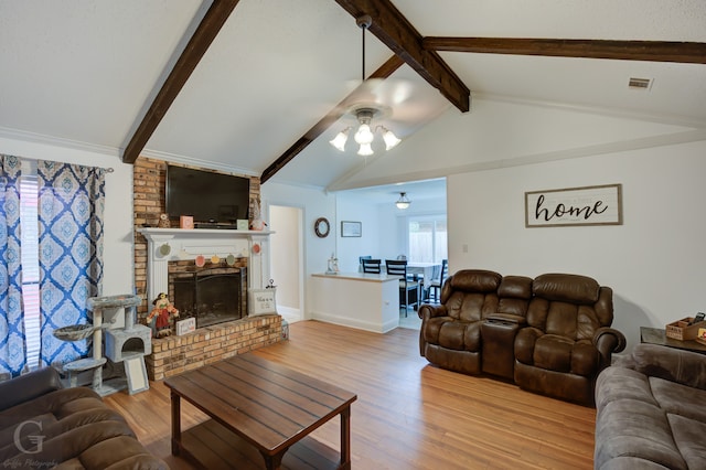 living room featuring a fireplace, light hardwood / wood-style floors, ceiling fan, and lofted ceiling with beams