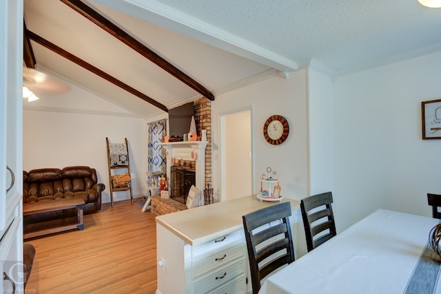 interior space featuring light hardwood / wood-style floors, ornamental molding, a textured ceiling, a fireplace, and vaulted ceiling with beams