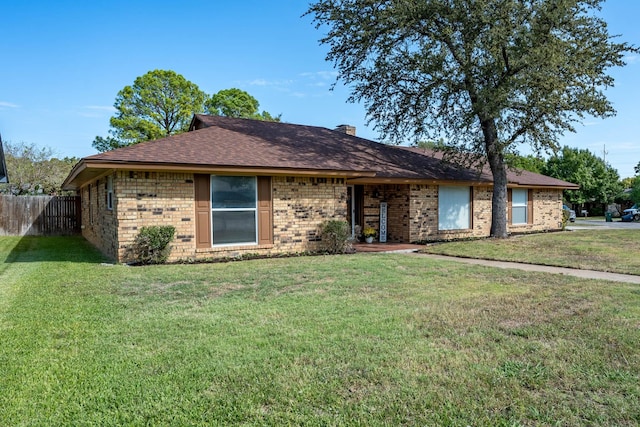 ranch-style home featuring brick siding, roof with shingles, a front yard, and fence