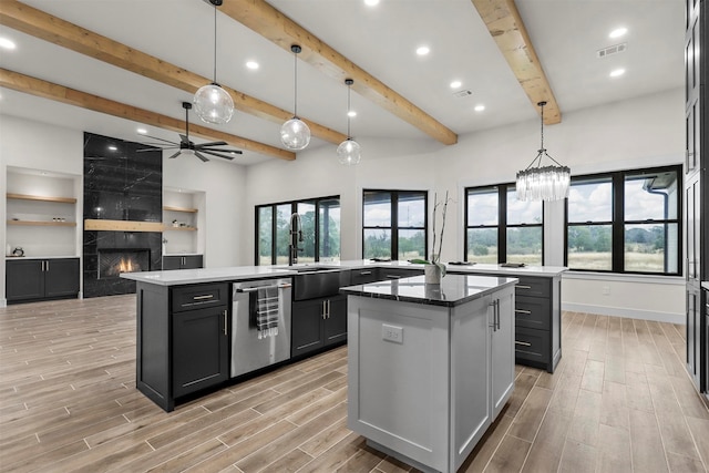 kitchen featuring a fireplace, stainless steel dishwasher, decorative light fixtures, and a center island