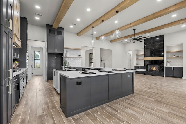 kitchen with light hardwood / wood-style flooring, a fireplace, decorative light fixtures, and a spacious island