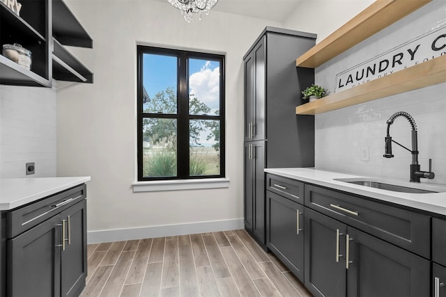 kitchen featuring light hardwood / wood-style floors, sink, an inviting chandelier, and decorative backsplash