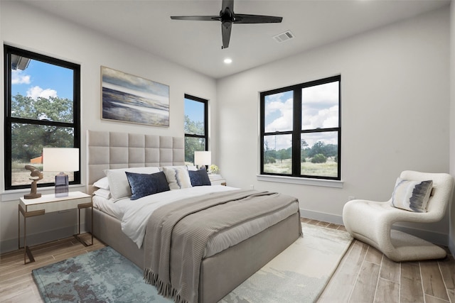 bedroom with light wood-type flooring, multiple windows, and ceiling fan