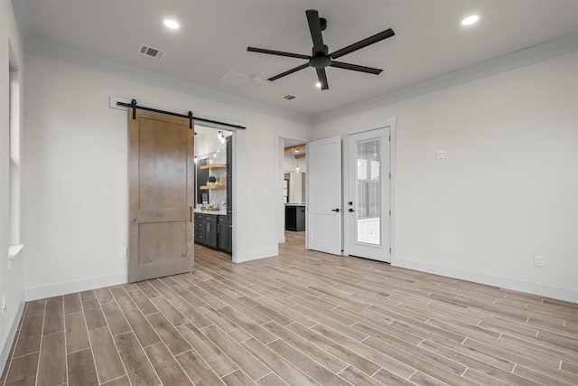 unfurnished room featuring ornamental molding, light wood-type flooring, a barn door, and ceiling fan