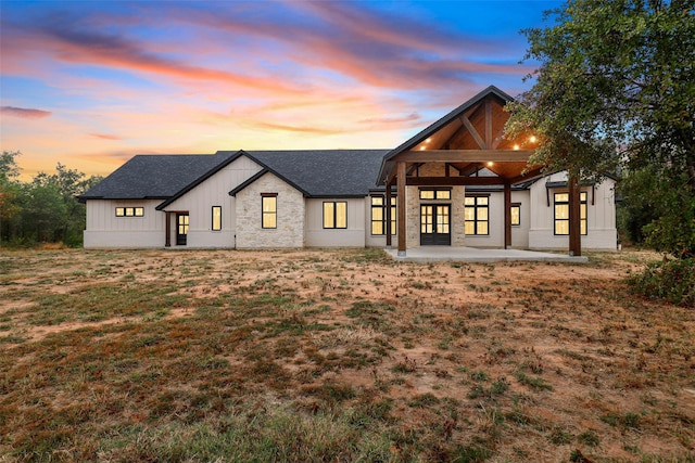 back house at dusk with a yard and a patio area