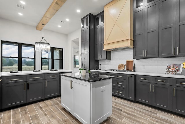 kitchen with custom range hood, beamed ceiling, an inviting chandelier, and light hardwood / wood-style floors