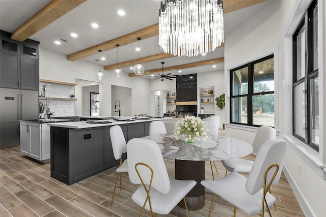 kitchen with a fireplace, beamed ceiling, dark wood-type flooring, and a center island with sink