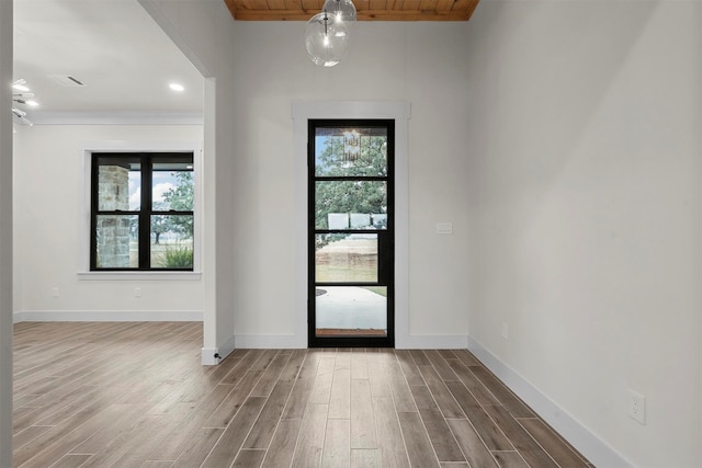 entrance foyer featuring hardwood / wood-style floors, wooden ceiling, a healthy amount of sunlight, and crown molding