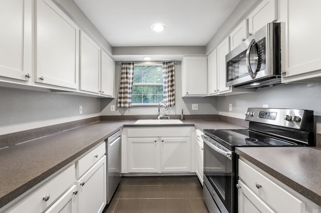 kitchen featuring dark tile patterned floors, white cabinets, sink, and stainless steel appliances