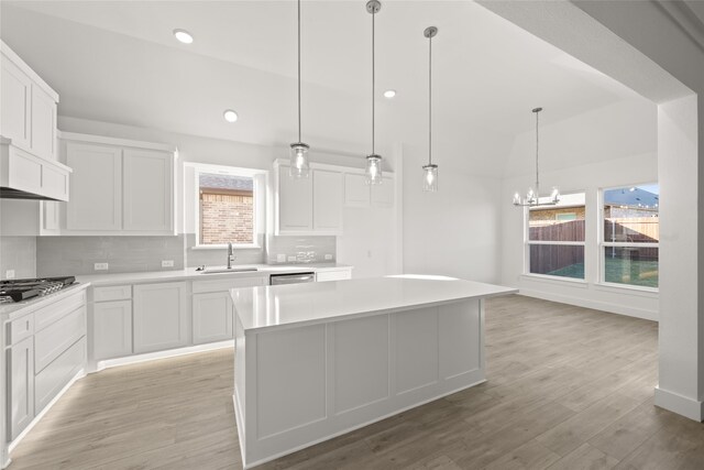 kitchen with white cabinets, a kitchen island, a healthy amount of sunlight, and sink