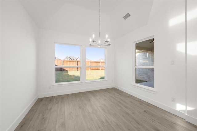 unfurnished dining area featuring ceiling fan with notable chandelier, light hardwood / wood-style floors, and lofted ceiling