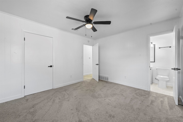 unfurnished bedroom featuring ornamental molding, ensuite bath, light carpet, and ceiling fan