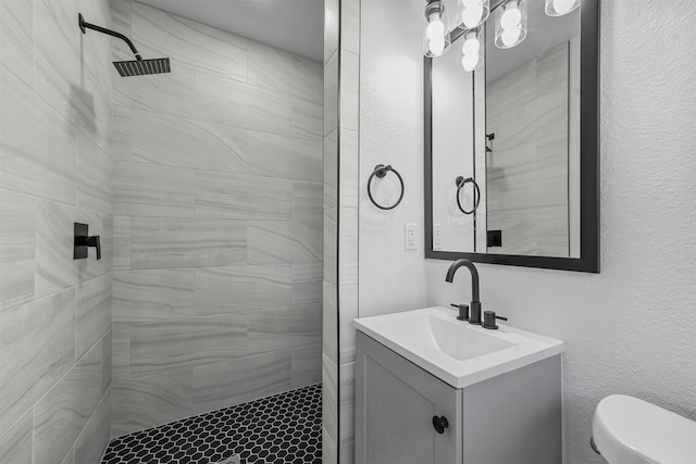 bathroom featuring tiled shower, vanity, and toilet