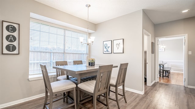 dining area with dark hardwood / wood-style floors, a textured ceiling, and a notable chandelier