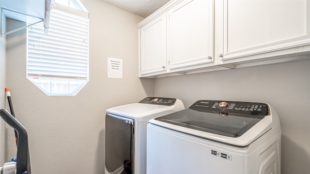 laundry room with washer and clothes dryer, cabinets, and a textured ceiling