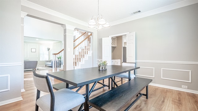 dining area featuring decorative columns, a chandelier, light wood-type flooring, and ornamental molding