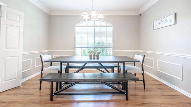 dining area featuring ornamental molding, light wood-type flooring, and an inviting chandelier