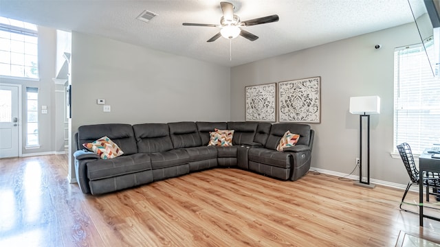 living room with light wood-type flooring, a textured ceiling, and ceiling fan