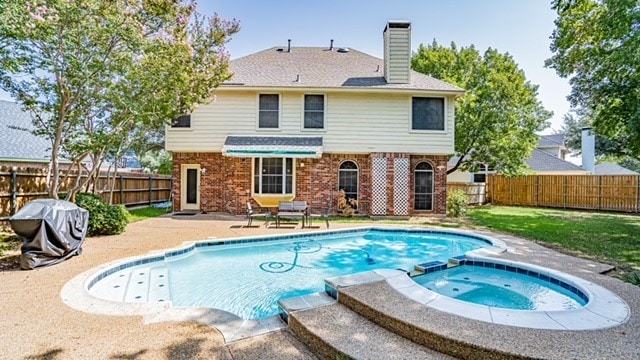 rear view of house featuring a swimming pool with hot tub and a patio area