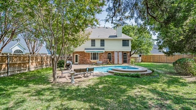 back of house featuring a fenced in pool, a yard, and a patio area