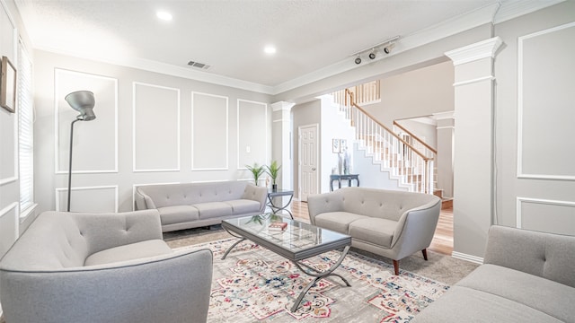 living room with ornate columns, light wood-type flooring, and ornamental molding