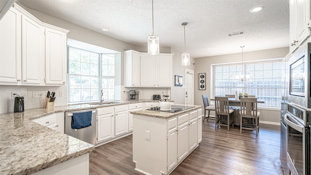 kitchen with white cabinets, plenty of natural light, sink, and a center island