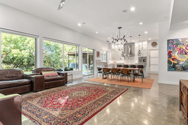 living room featuring a chandelier and concrete floors