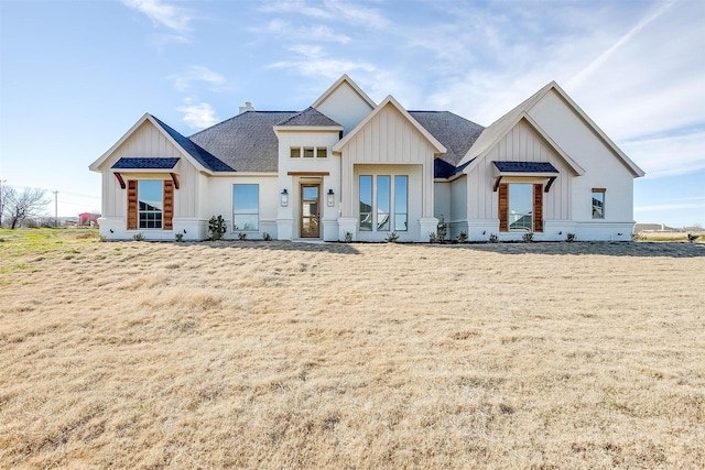 modern farmhouse with board and batten siding, a front yard, and roof with shingles