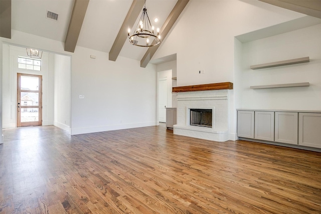 unfurnished living room featuring an inviting chandelier, a brick fireplace, visible vents, and beamed ceiling