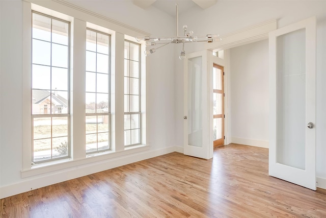 spare room with light wood-type flooring and an inviting chandelier