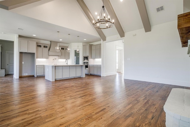 unfurnished living room with dark wood finished floors, visible vents, a sink, and beamed ceiling