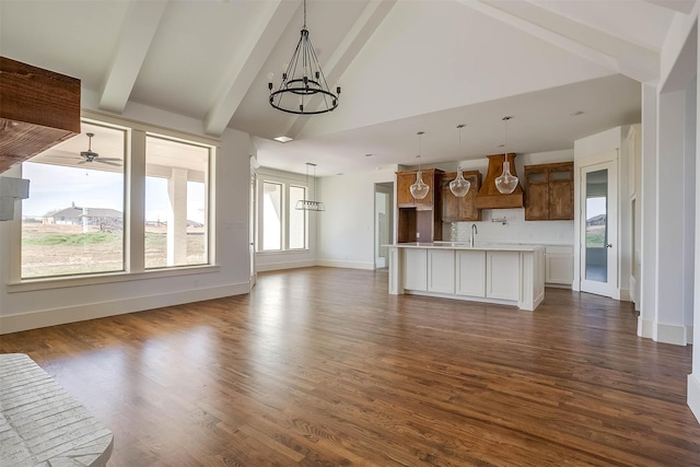 unfurnished living room featuring beam ceiling, dark hardwood / wood-style flooring, high vaulted ceiling, sink, and ceiling fan with notable chandelier