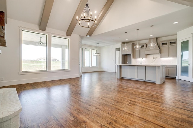 unfurnished living room featuring dark wood-style floors, a notable chandelier, baseboards, and beamed ceiling