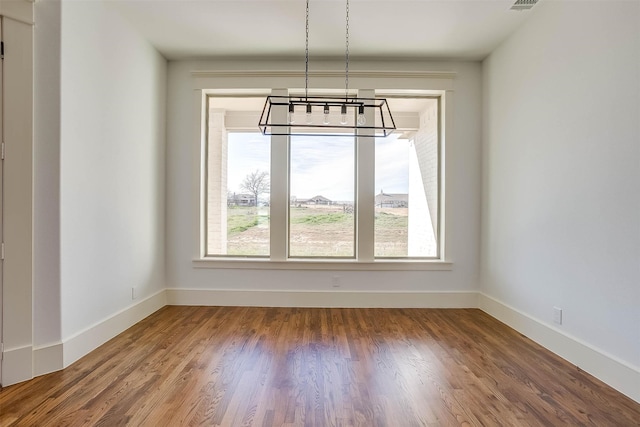 unfurnished dining area featuring hardwood / wood-style flooring and a notable chandelier