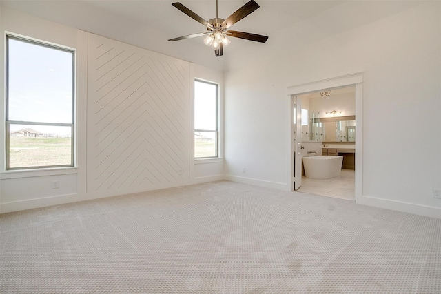 empty room with a ceiling fan, light colored carpet, and baseboards