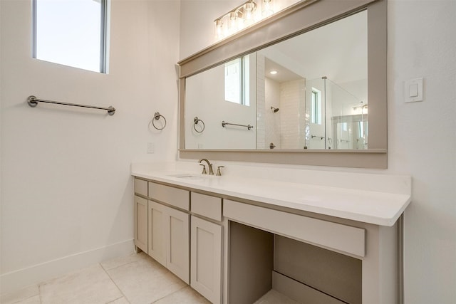 bathroom with a tile shower, tile patterned flooring, vanity, and baseboards