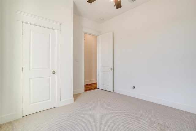 unfurnished bedroom featuring light colored carpet, ceiling fan, and baseboards