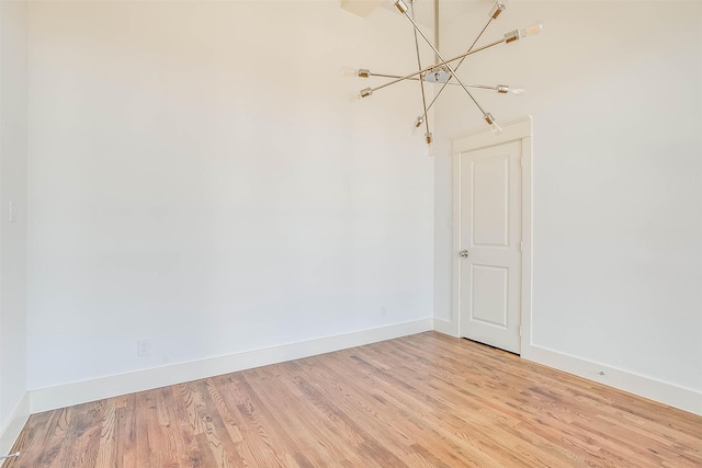 empty room with light hardwood / wood-style flooring and a notable chandelier