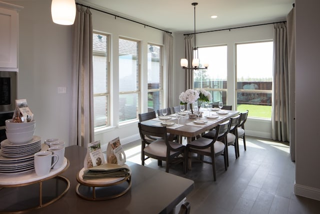 dining space featuring dark wood-type flooring, a notable chandelier, and plenty of natural light