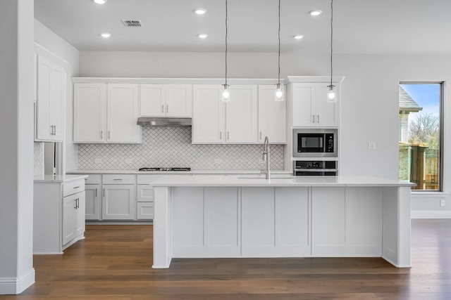 kitchen with light countertops, dark wood-style floors, under cabinet range hood, and stainless steel appliances