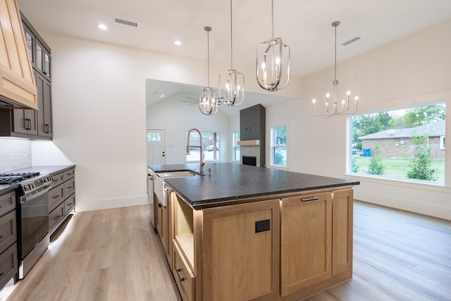 kitchen featuring pendant lighting, appliances with stainless steel finishes, lofted ceiling, and an island with sink