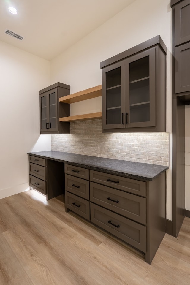 kitchen with decorative backsplash, light hardwood / wood-style flooring, and dark stone countertops