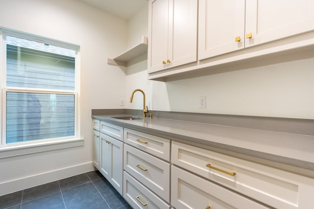 interior space with white cabinetry, sink, and dark tile patterned floors