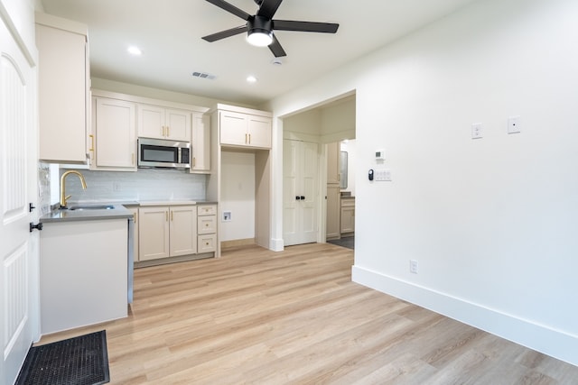 kitchen featuring sink, ceiling fan, backsplash, white cabinets, and light wood-type flooring