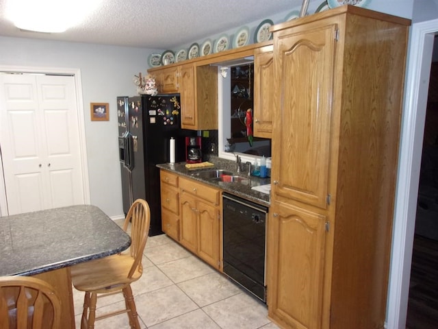 kitchen with black appliances, a textured ceiling, sink, a breakfast bar area, and light tile patterned floors