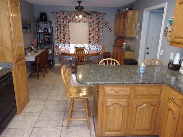 kitchen with black dishwasher, dark stone counters, ceiling fan, and light tile patterned floors