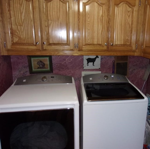 clothes washing area featuring washer and clothes dryer and cabinets