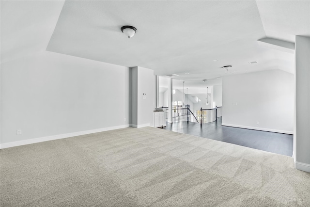 empty room with vaulted ceiling and dark carpet