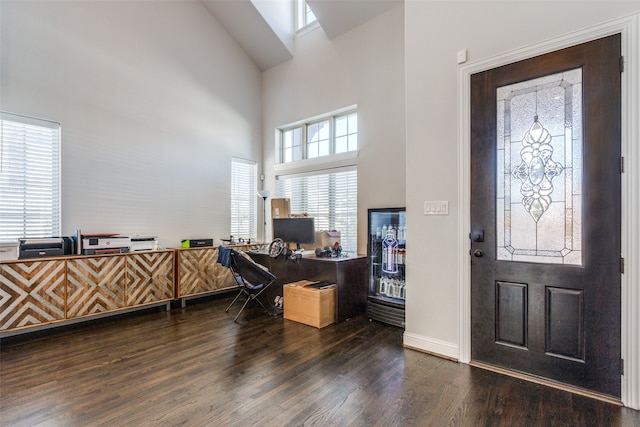 entryway with a towering ceiling, a wealth of natural light, and dark hardwood / wood-style floors